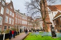 Begijnhof courtyard with tourists, statue and historic houses in Amsterdam, Netherlands