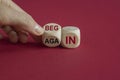 Begin again symbol. Businessman turns wooden cube and changes the red words begin to again. Beautiful red background. Business and