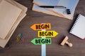 Begin concept. Paper signpost on a wooden desk Royalty Free Stock Photo