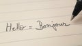 Beginner French language learner writing Hello word Bonjour for homework on a notebook