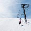 Beginner little girl with skis ascends with ski lift Royalty Free Stock Photo