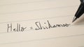Beginner Swahili language learner writing Hello formal word Shikamoo for homework on a notebook