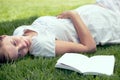 The beginning of a beautiful story. A pretty woman lying on the grass outdoors and relaxing in the sunshine.