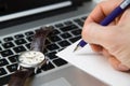 The beginning of the day, the clock on the laptop keyboard, hand holding a blue pen, workplace.