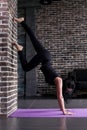 Beginning female yogi practicing yoga inversion poses standing on hands upside down leaning against wall in fitness club Royalty Free Stock Photo