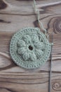 The beginning of handmade crocheted cotton organic doily, coaster or napkin, on wooden background. Metal crocheting hook