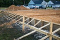 The beginning of a new construction build in a neighborhood with the foundation poured, dirt added and the wood based