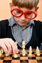 The beginning of a new game of chess with a young smart chess player in red glasses Royalty Free Stock Photo