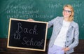 Beginning of new school season. Woman teacher formal suit holds blackboard inscription back to school. Lady educator in Royalty Free Stock Photo