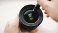 Beginning photographer or video cameraman is carefully cleaning the front glass of the lens. Royalty Free Stock Photo