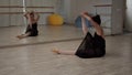 At the beginning of the training, the ballerina stretches the muscles of her back and legs while sitting on the floor in