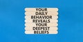 Behavior symbol. Concept words Your daily behavior reveals your deepest beliefs on wooden stick. Beautiful blue table blue