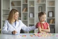 Behavior Therapy For Kids. Smiling Psychotherapist Woman Working With Grumpy Little Girl
