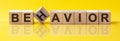 BEHAVIOR Word made of building blocks on a light yellow background