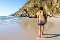 Behind of attractive surfer walking in sand by water