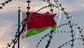 Behind barbed wire flag of Belarus against the sky, 3d rendering. Concept: international sanctions, totalitarian regime,