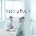 Behind closed doors. Closeup of a glass door reading meeting room with business people blurred in the room behind. Royalty Free Stock Photo