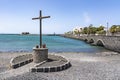 Behind a cross and the bridge to the inner harbor of Arrecife, you can see in the distance the old fortress Castillo de San Gabri