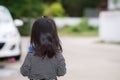 Behind the little girl stood on road. In front of her there was blurry car. Concept safety of young children on public road.