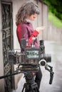 Behind scene. Female cameraman with her camera holds mobile phone