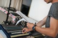 Sound technician at theatre adjusting sound elements, looking at script