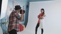 Behind the scenes on photo shoot: professional photographer working in studio by taking photos of black model Royalty Free Stock Photo