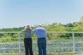 Behind senior American couple watching bluebonnets blooming field over ranch fence in Texas