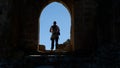 Behind shot of a man standing near the arch of an old building and enjoying the view on a sunny day