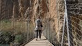 Behind shot of a tourist crossing a suspension bridge in Valencia, Spain on a sunny day