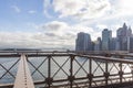 Behind the steel structures of the Brooklyn Bridge you can see the skyscrapers of Manhattan and in the distance the Statue of Lber Royalty Free Stock Photo