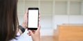 Behind of woman is holding a white blank screen smartphone while standing over blurred background Royalty Free Stock Photo