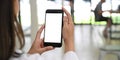 Behind of woman is holding a white blank screen smartphone while standing over blurred background Royalty Free Stock Photo