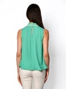 From behind. Young beautiful woman posing in blue mint shirt and beige gray pants on a white