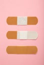 Beige adhesive bandages on pink background. Medical plasters. Vertical photo Royalty Free Stock Photo