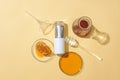 On a beige background, a cosmetic bottle, beeswax on a petri dish, honey in a glass jar, and a honey drizzle form a composition. Royalty Free Stock Photo