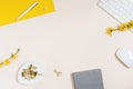 On a beige background flat lay with a yellow flower, a notepad keyboard and paper clips, a female floral desktop.