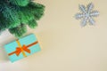 On a beige background a gift in a turquoise box with an orange bow, a snowflake and a spruce branch. A place for Royalty Free Stock Photo