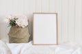Beige blank wooden picture frame mockup. Artistic table still life composition with pink peony flowers in straw basket Royalty Free Stock Photo
