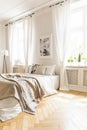 Beige blanket on bed and poster in white bedroom interior with d