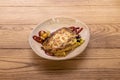 Beige bowl with vegetable lasagna and cheese gratin with pumpkin blossoms