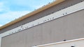 A beige building with multiple ledges lined with pigeons.