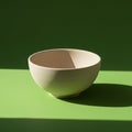 A beige ceramic bowl is placed on a bright green surface, with a matching green Royalty Free Stock Photo