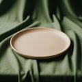 A beige ceramic plate is centered on a draped green fabric, creating a contrast betwee Royalty Free Stock Photo
