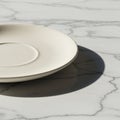 A beige ceramic saucer with a smooth, matte finish is placed on a white marble surfac Royalty Free Stock Photo