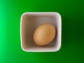 Beige chicken egg in a white square deep bowl
