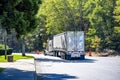 Beige classic big rig semi truck transporting cargo in tented dry van semi trailer running from the rest area by highway road Royalty Free Stock Photo