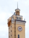 Beige clock tower, spire, small windows and a thin long staircase, against the sky Royalty Free Stock Photo