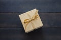 Beige closed gift box with gold color ribbon on blue table background Royalty Free Stock Photo