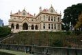 Beige gothic revival Parliamentary Library with classic colonnade porch entry and red roof on mound, Wellington, New Zealand