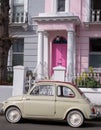 Beige colour vintage Fiat 500 classic car parked in front of a house with a pink door on a street in Notting Hill, Londond UK Royalty Free Stock Photo